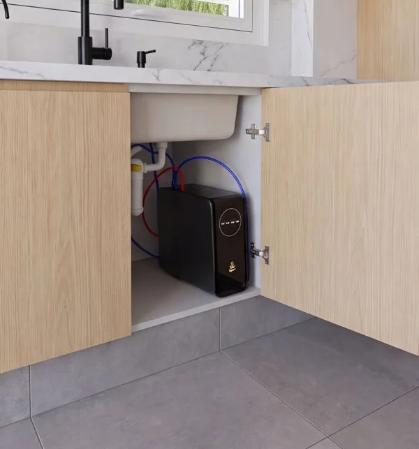 Equipo instalado en el mueble bajo el fregadero con los tubos de entrada, salida y rechazo